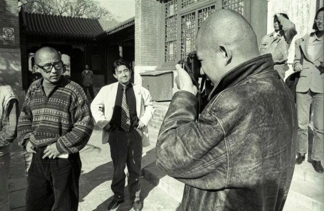 方力钧变身摄影师。左边是杨少斌和杨茂源。（1996年4月20日摄于万寿寺北京艺术博物馆内“大众样板”艺术展现场）